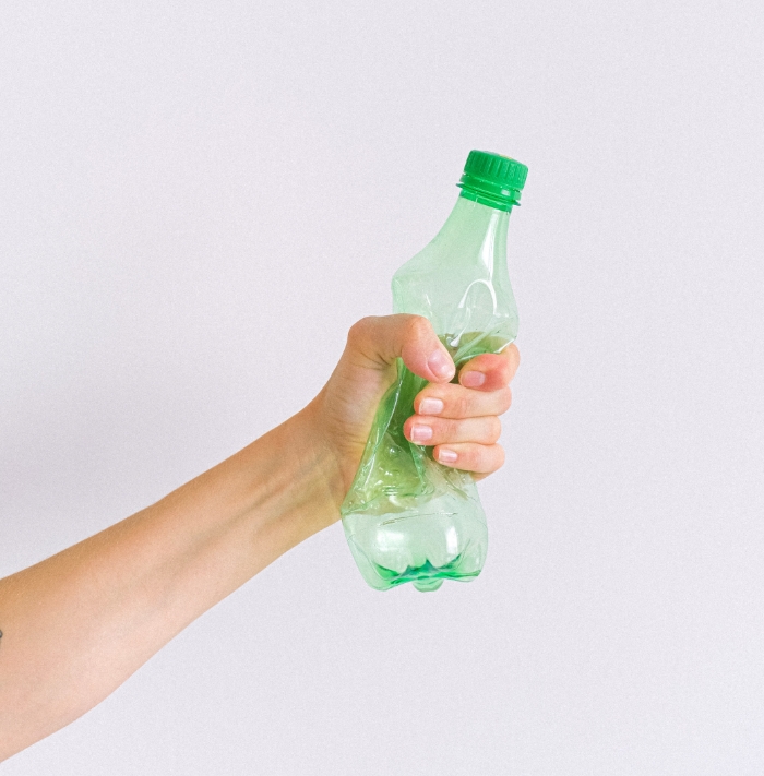 person crushing plastic bottle in hand